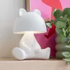 A white bear-shaped table lamp is displayed on a shelf. Náhled obrázku produktu