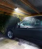 A black car parked under a wooden carport with a light shining down. Produktbild-Vorschau