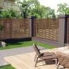 A backyard patio with a wooden deck, chairs, and a slatted fence. Produktbild-Vorschau