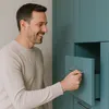 A man is opening a drawer on a teal cabinet. Produktbild-Vorschau