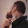 A man is shaving his beard with a razor. Voir les images du produit