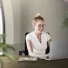 A woman is working on a laptop at a desk in an office. Produktbild-Vorschau
