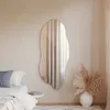 A bedroom scene with a mirror on the wall, a bed, and a vase of dried flowers. Produktbild-Vorschau