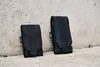 Two black pouches are placed on a concrete surface against a concrete wall. Náhled obrázku produktu