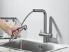 A hand is shown pulling a flexible hose from a kitchen faucet over a stainless steel sink. Anteprima dell’immagine prodotto