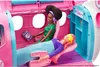 Two Barbie dolls are inside a pink toy airplane playset. One doll is seated in a pilot's seat, and the other is lying down in a passenger seat with a sleep mask on. Produktbild-Vorschau
