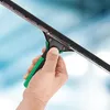 A hand holding a window squeegee with a blurred blue and white background. Podgląd zdjęcia produktu