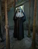 A person dressed as a scary nun stands in a derelict building. Produktbild-Vorschau