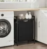A laundry room scene with a washing machine, a black laundry basket with a shelf, and towels. Podgląd zdjęcia produktu