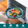 A hand wearing an oven mitt is placing a plate of food onto a rack inside an oven. Náhled obrázku produktu