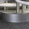 A close-up view of the base of a modern ceiling light fixture, showing its metallic construction and circular design. Podgląd zdjęcia produktu