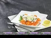 A prepared dish of fish and spiralized carrots served on a white plate, with cutlery and a lemon slice. Produktbild-Vorschau