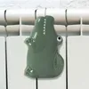 A green ceramic crocodile-shaped radiator humidifier is attached to a white radiator. Produktbild-Vorschau