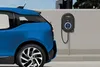 A blue electric car is parked next to a wall-mounted EV charger. Produktbild-Vorschau