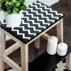 A step stool with a black and white chevron pattern on the top surface, decorated with a potted green plant and two white candles on the lower shelf. Podgląd zdjęcia produktu