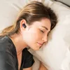 A woman sleeping in bed with earbuds in her ears. Produktbild-Vorschau