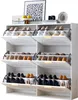 A white shoe cabinet with multiple shelves and flip-down doors, filled with various shoes. Decorative items are placed on top of the cabinet. Produktbild-Vorschau