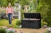 A woman walks past a large black storage box in a garden setting. Anteprima dell’immagine prodotto