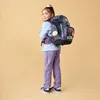 A young girl wearing a backpack, posing for a photo. Náhľad obrázku produktu