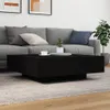 A modern living room scene with a black coffee table in the foreground and a gray sofa in the background. Produktbild-Vorschau