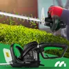 A person is using an electric hedge trimmer to trim a bush, with leaves flying around. Náhľad obrázku produktu