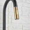 A close-up shot of a black and gold kitchen faucet with water running. Produktbild-Vorschau