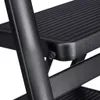 A close-up view of a black step stool, showing the texture of the steps and the metal frame. Voir les images du produit