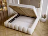 A bed with its storage compartment open, showing the slatted base and the interior storage space. The bed is upholstered in beige fabric and sits on a wooden floor. Produktbild-Vorschau