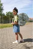 A young girl is walking outdoors with a large backpack on her back. Voir les images du produit