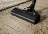 A vacuum cleaner head is cleaning a wooden floor with debris. Produktbild-Vorschau