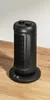 A black tower heater sits on a wooden surface against a light gray background. Produktbild-Vorschau