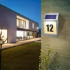 A modern house at dusk with a solar-powered house number light illuminated on the wall. Produktbild-Vorschau