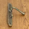 A close-up shot of a door handle set mounted on a wooden door. Produktbild-Vorschau