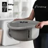 A person is holding a gray plastic basin in a laundry room setting. Produktbild-Vorschau