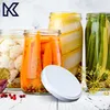Jars of pickled vegetables (cauliflower, carrots, zucchini, green beans) and a white lid on a white wooden surface, with dill sprigs and cranberries scattered around. Produktbild-Vorschau