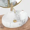 A close-up view of a marble countertop sink with a gold faucet. Produktbild-Vorschau