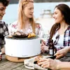People enjoying a barbecue outdoors by a body of water. Produktbild-Vorschau