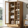 A wooden display cabinet with glass doors and drawers, filled with books and decorative items, placed in a room with a window and curtains. Podgląd zdjęcia produktu