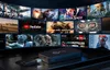 A black media player device is shown in the foreground, with a collage of movie and streaming service posters displayed on screens in the background. Náhľad obrázku produktu
