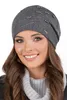 A woman wearing a dark grey beanie with pearl and rhinestone embellishments. Náhled obrázku produktu