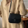 A person wearing a tan coat and a black crossbody bag. Náhľad obrázku produktu