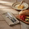 A table setting with cutlery, bread, and roasted vegetables. Anteprima dell’immagine prodotto