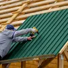 A person is installing green corrugated metal roofing panels on a wooden structure. Náhľad obrázku produktu