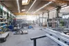 A wide shot of a workshop with various metal structures and equipment. Voir les images du produit