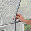 A hand is shown adjusting a metal pole of a greenhouse frame, with the white transparent PE plastic sheeting visible in the background. Produktbild-Vorschau