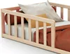 A close-up view of a wooden baby bed with bedding and pillows. Voir les images du produit