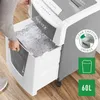A person is shown pulling out the shredded paper bin from a paper shredder. Voir les images du produit