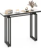A narrow console table with a marble-look top and black metal legs, decorated with a small radio, a cup of coffee, a decorative object, and a vase of dried flowers.