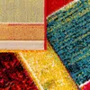 A close-up view of a colorful, abstract patterned rug, showing the texture and weave of the fabric. Produktbild-Vorschau