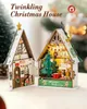 Two miniature wooden Christmas houses, one open to reveal an interior scene with a Christmas tree and gifts, the other closed with a door and window. Produktbild-Vorschau